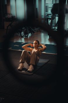 A focused adult woman doing sit-ups in a modern gym.