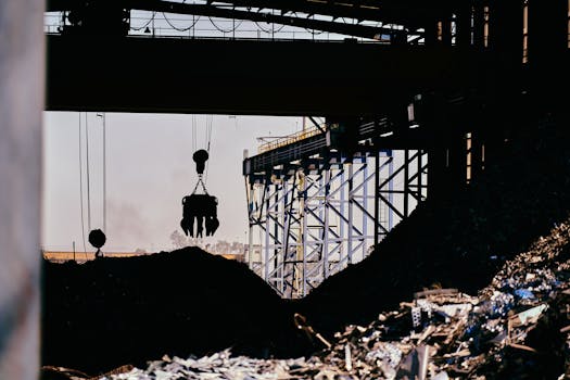 Silhouette of industrial crane operating at a metal recycling facility.