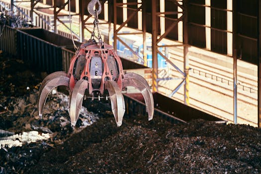 A claw crane inside a recycling facility lifting scrap metal, highlighting industrial processes.