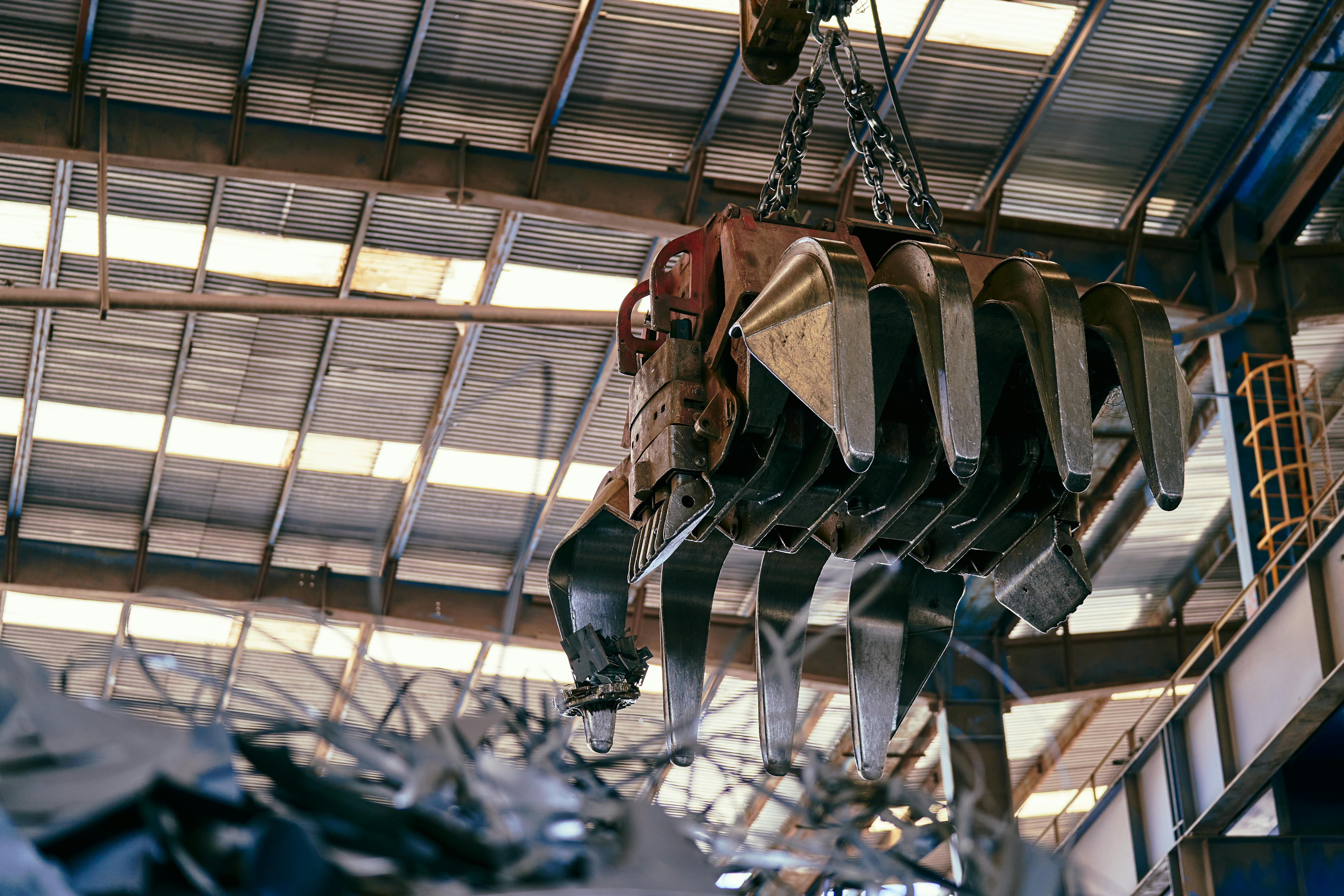 Gratis Stor industrikran håndterer skrotmetal i et lagermiljø. Lagerfoto