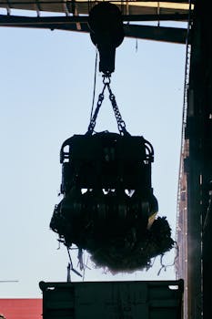 Dramatic silhouette of a scrap crane lifting debris in an industrial setting, highlighting heavy machinery.