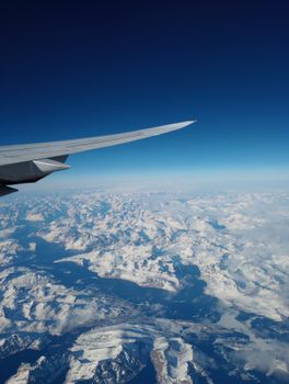 Stunning aerial shot of Greenland's snow-covered landscape with an airplane wing in view.