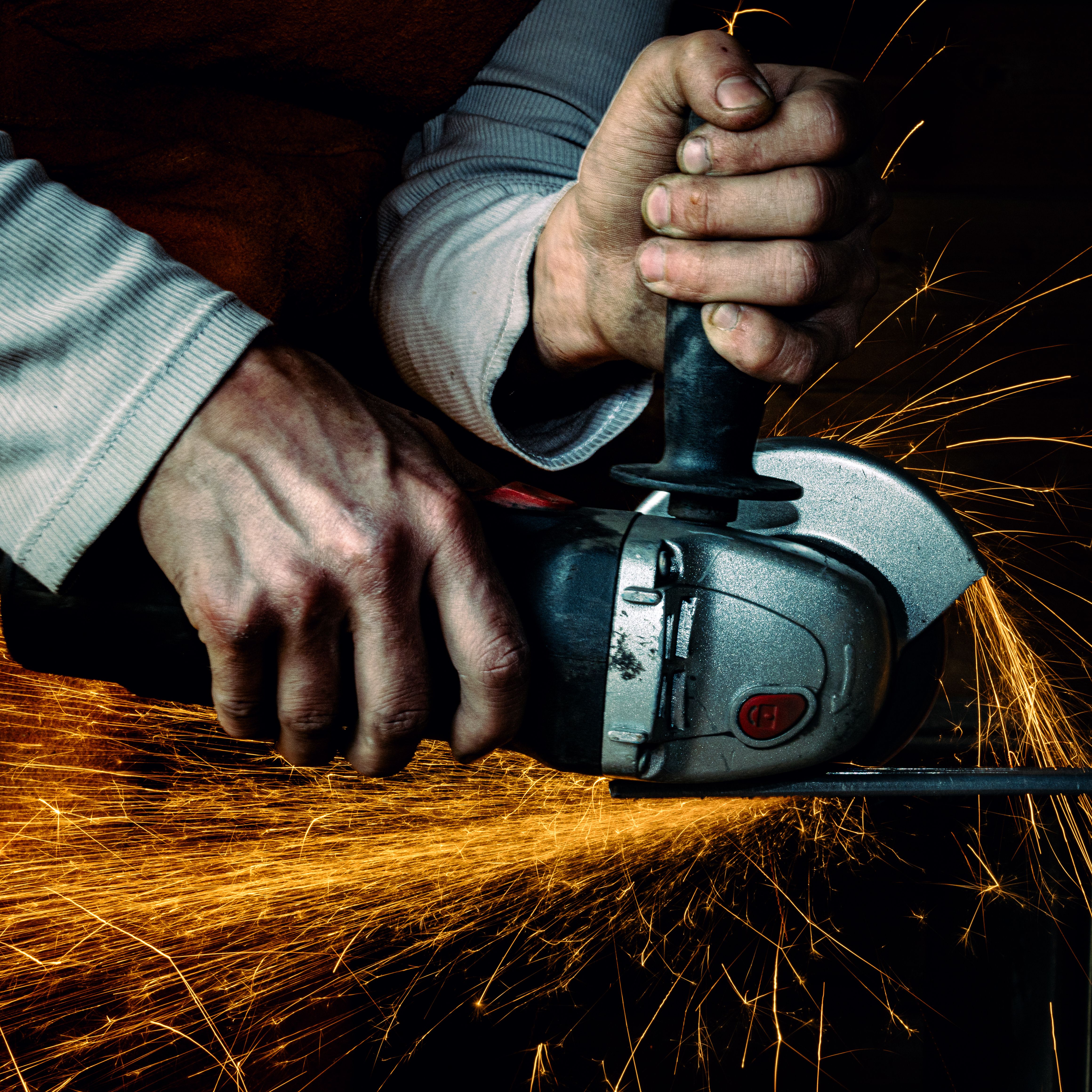 A worker skillfully operating an electric grinder, producing dynamic sparks.
