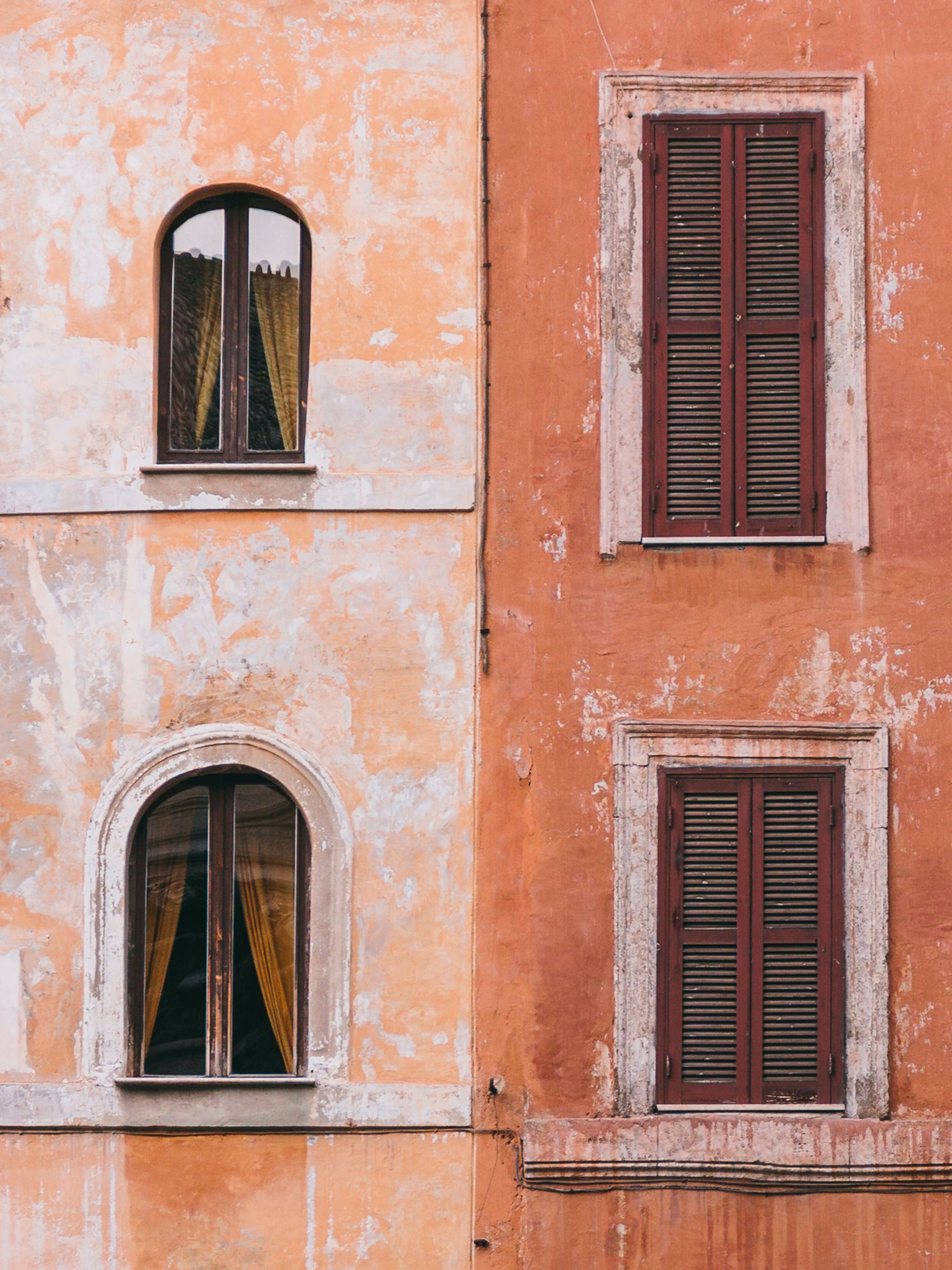 Close-up of rustic Italian architecture in Rome with weathered walls and windows.