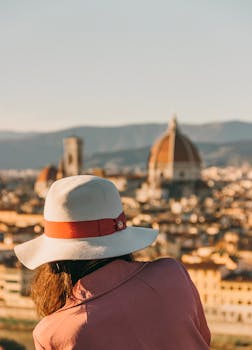 A woman in a hat enjoys a panoramic view of Florence, Italy at sunset.