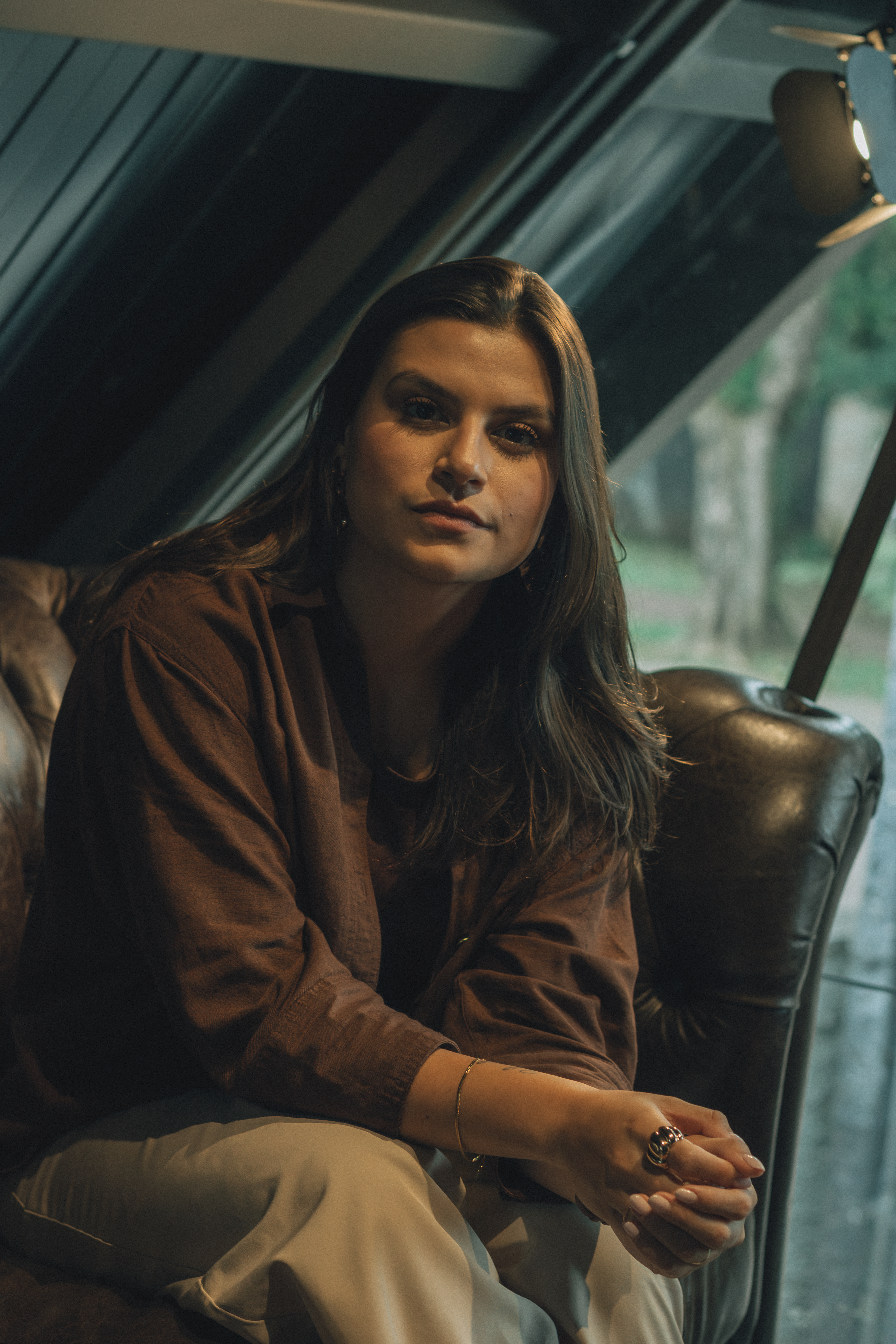 Relaxed portrait of a woman sitting indoors with natural light.