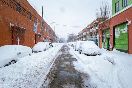 Free A snowy winter scene in Astoria, New York showing cars and buildings covered in snow. Stock Photo