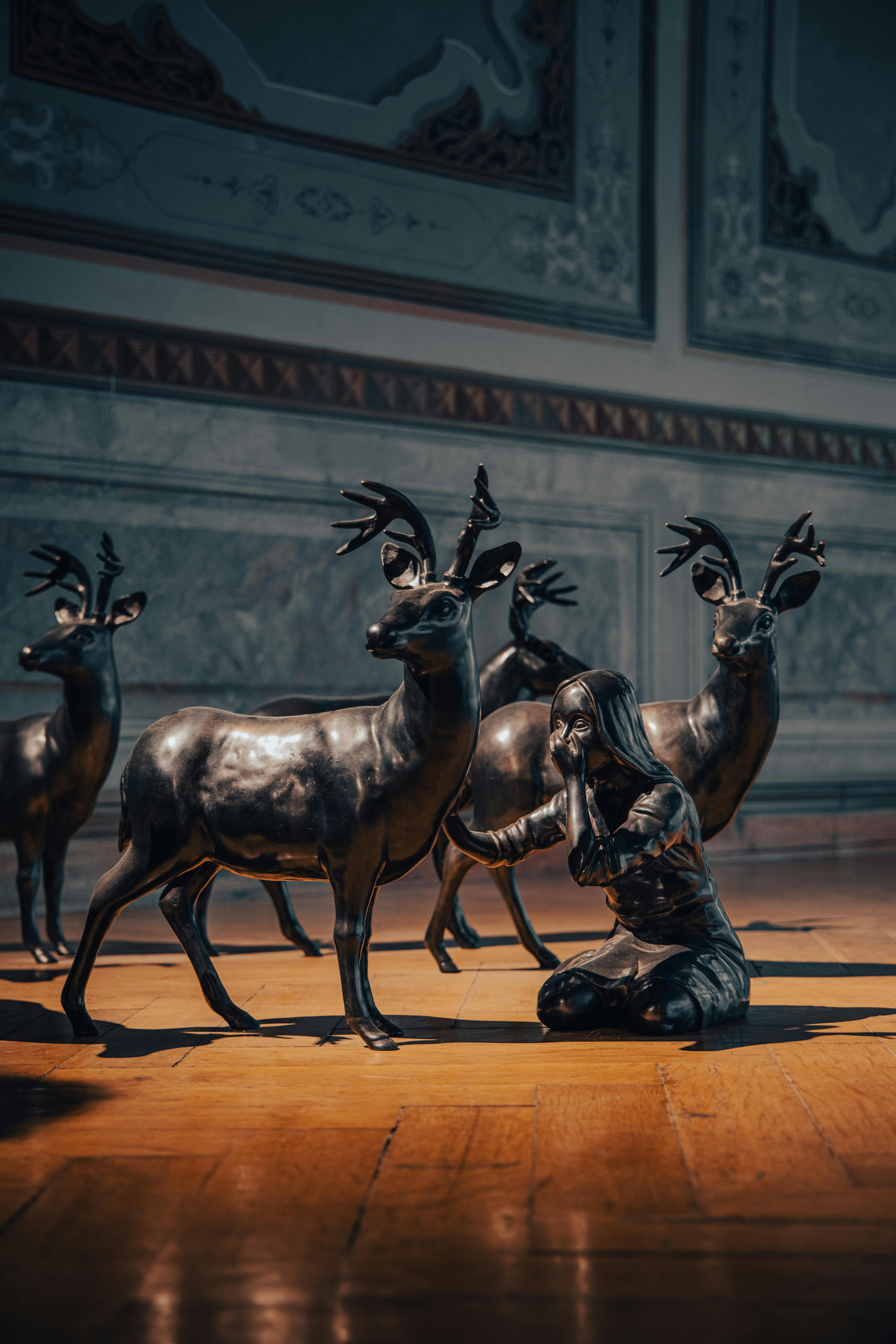 Free Bronze sculptures of deer and a person in a classic indoor setting, creating a serene atmosphere. Stock Photo