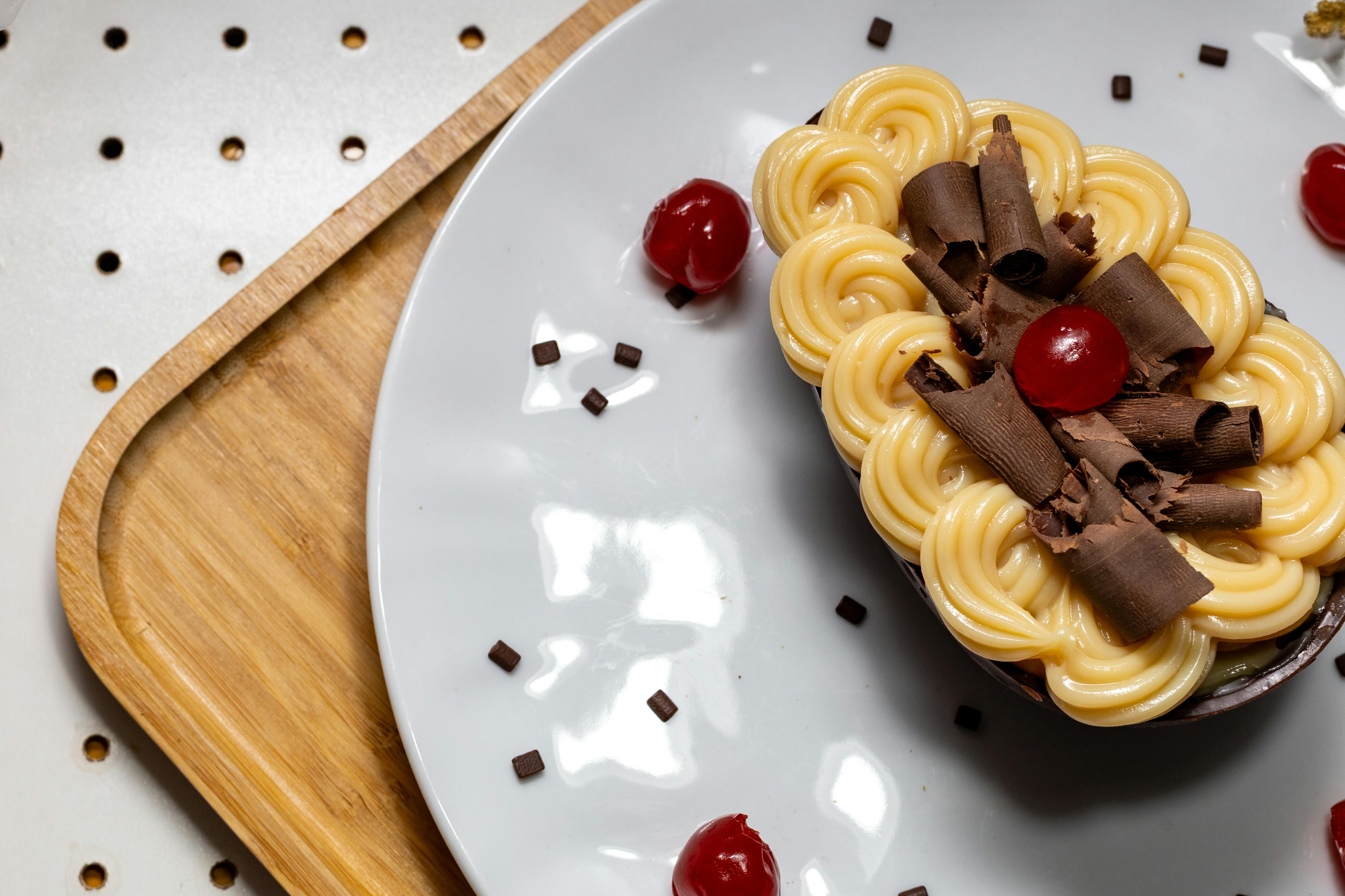 Gratis Tampilan dekat hidangan penutup mewah yang dihiasi dengan serutan cokelat dan ceri di atas piring putih. Foto Stok