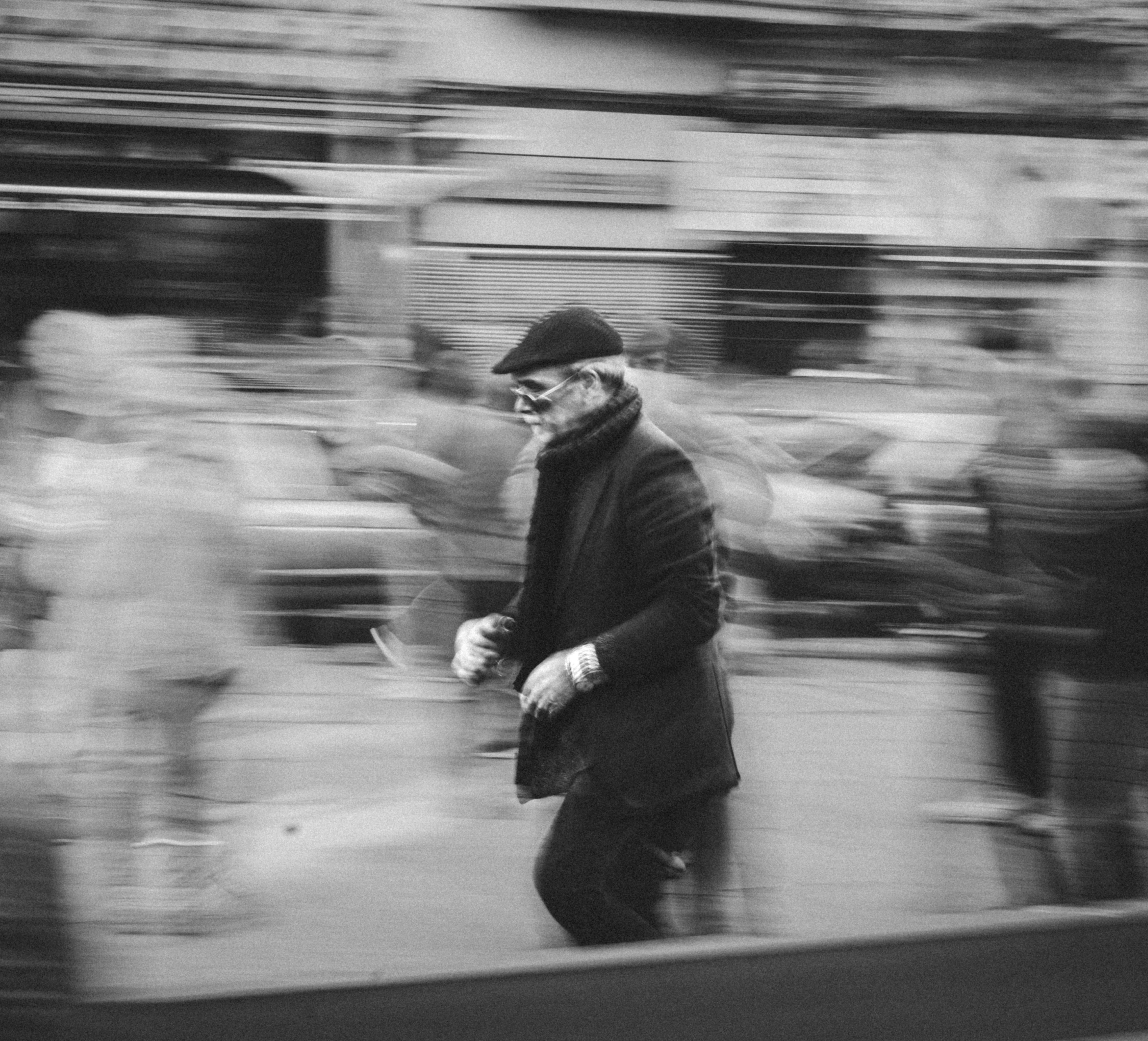 Free Elegant man walking with motion blur effect in a bustling street, captured in black and white. Stock Photo