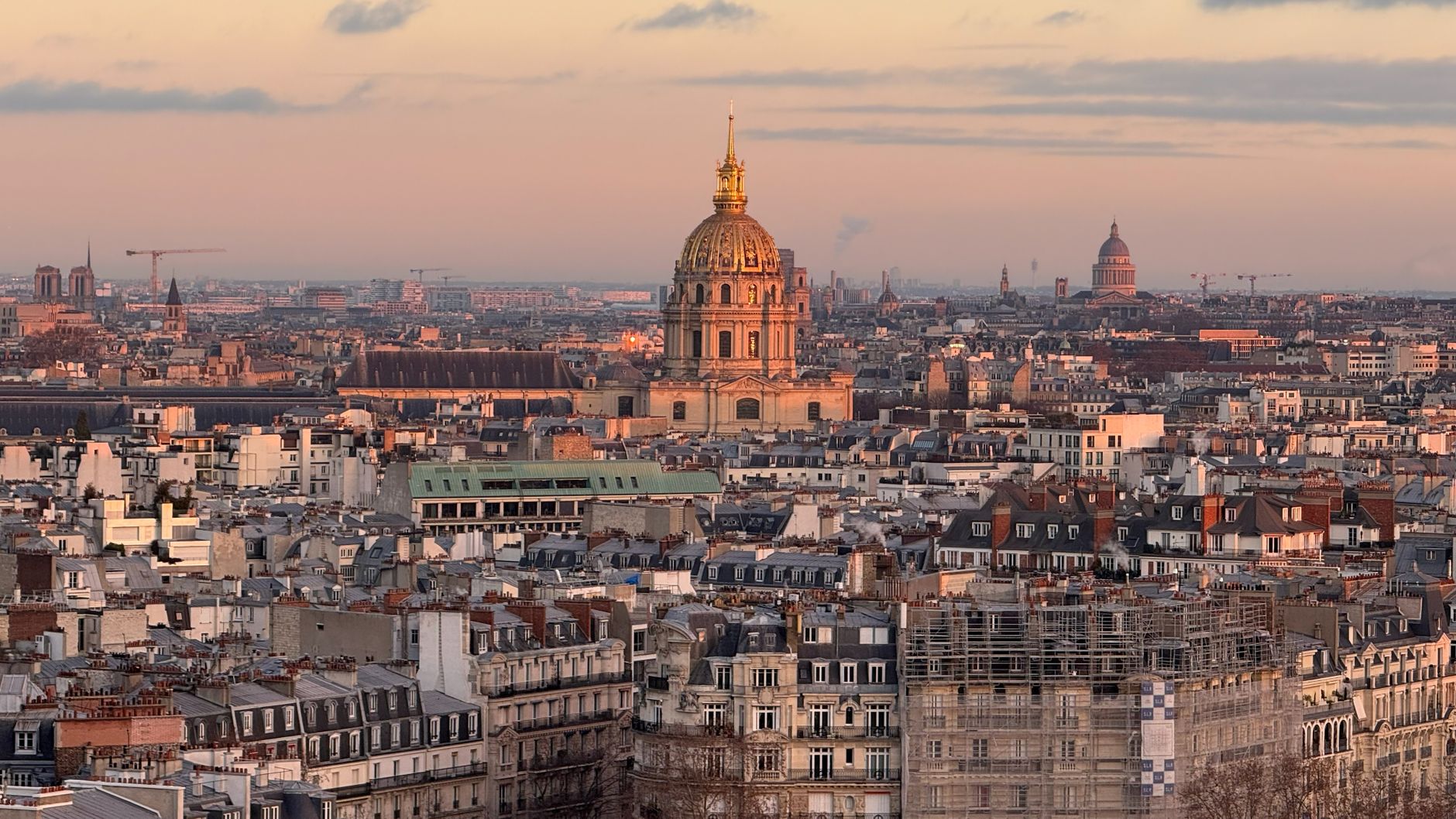 Explore Paris with an aerial view of iconic landmarks and traditional rooftops at sunset.