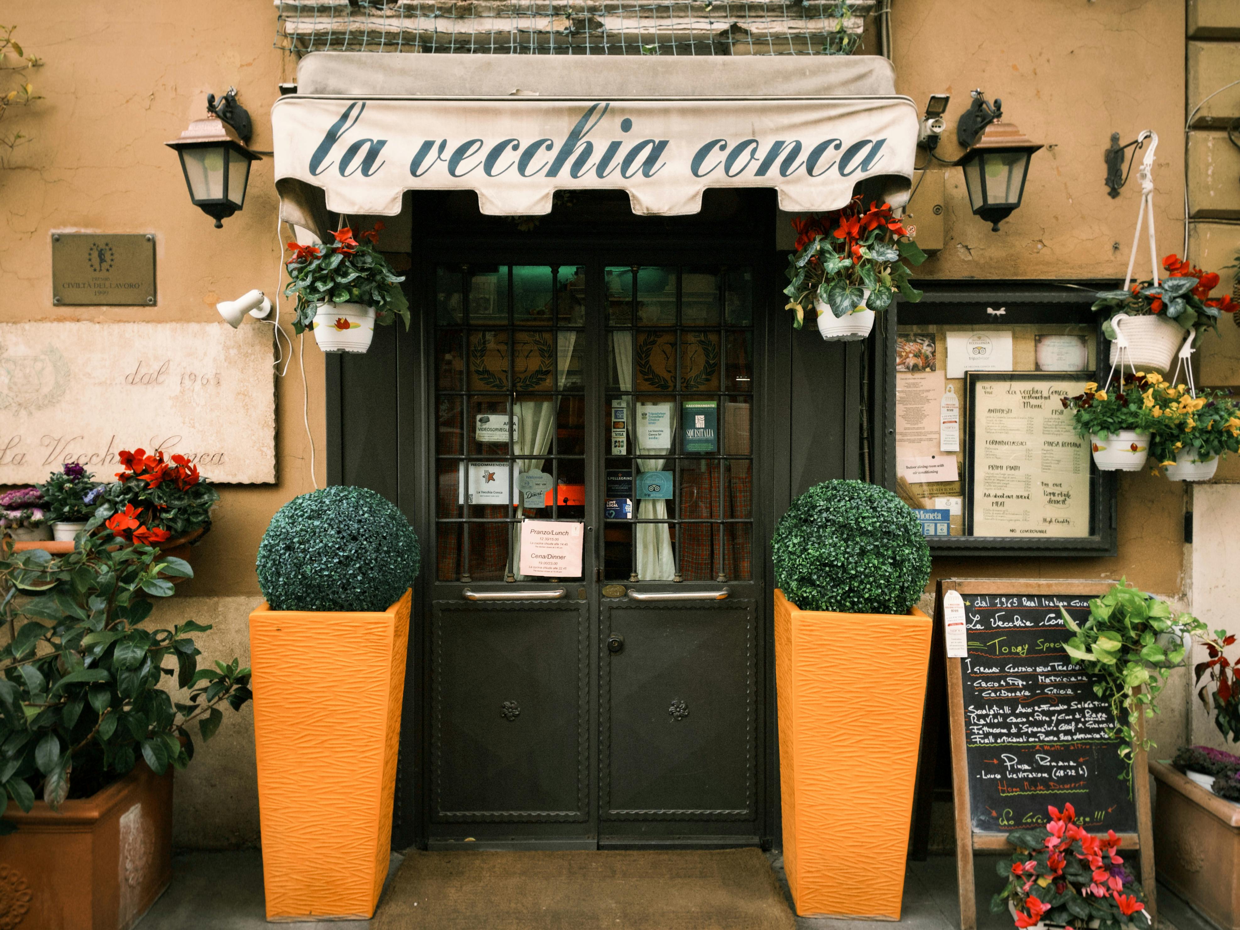 бесплатная Фасад очаровательного итальянского ресторана, украшенный яркими цветами и элементами декора в деревенском стиле. Стоковое фото