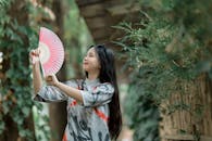 Young Woman Holding Pink Fan Outdoors
