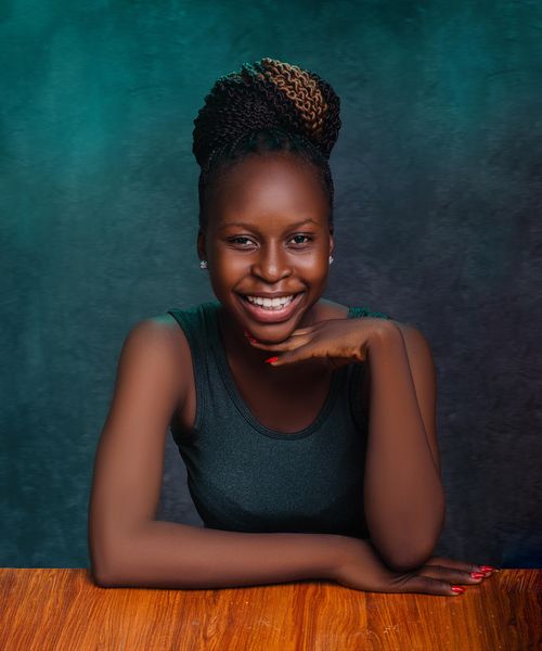 Free Portrait of a smiling woman in a studio setting with a wooden table. Stock Photo