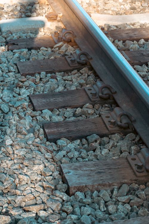 Free Detailed shot of railway tracks with gravel, showcasing industrial texture and rusty elements. Stock Photo