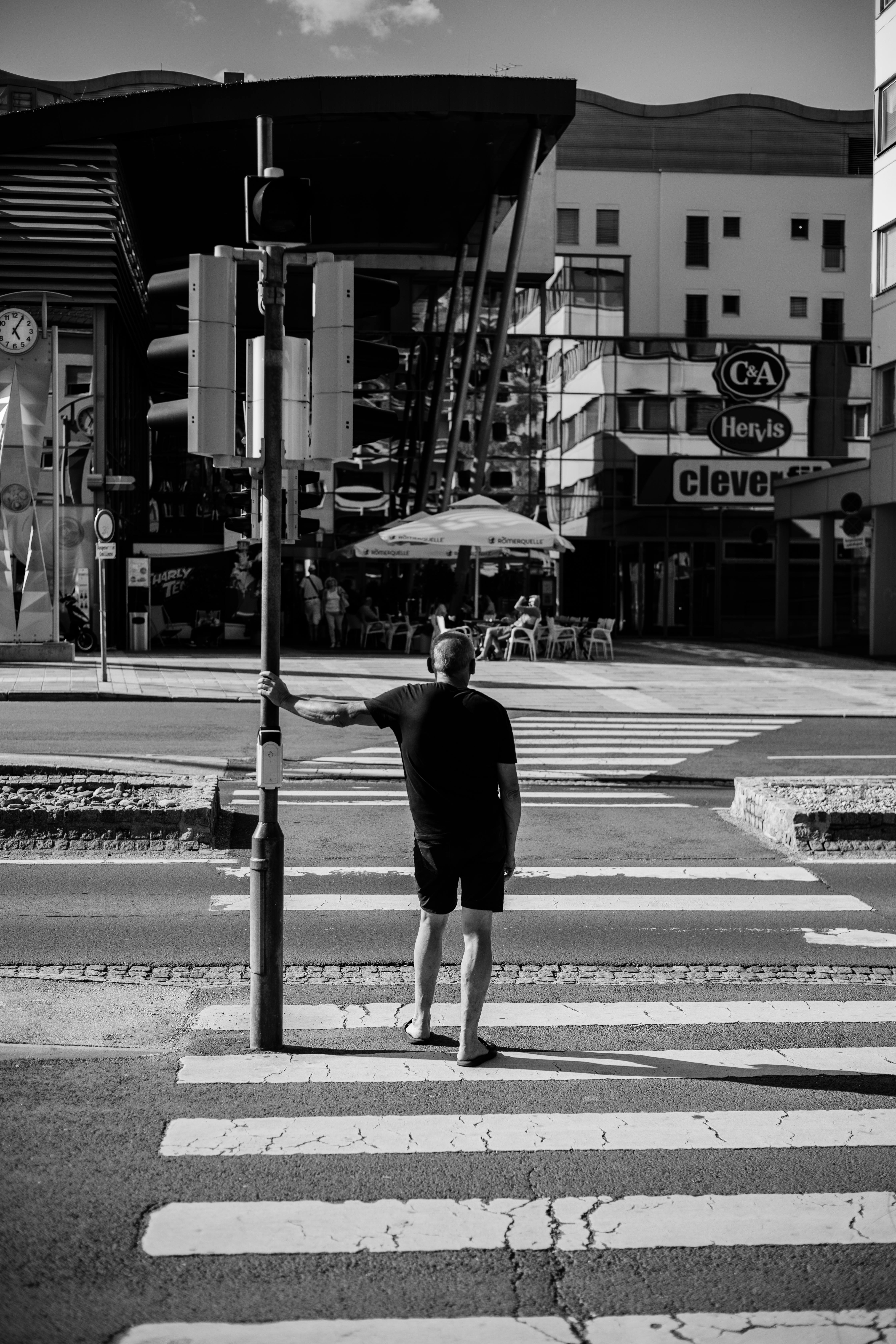 Gratis Uomo in attesa sulle strisce pedonali a Kapfenberg, in Austria, in un paesaggio urbano in bianco e nero. Foto a disposizione