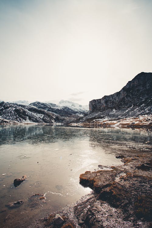 Icy lake near ridge under cloudy sky in wintertime