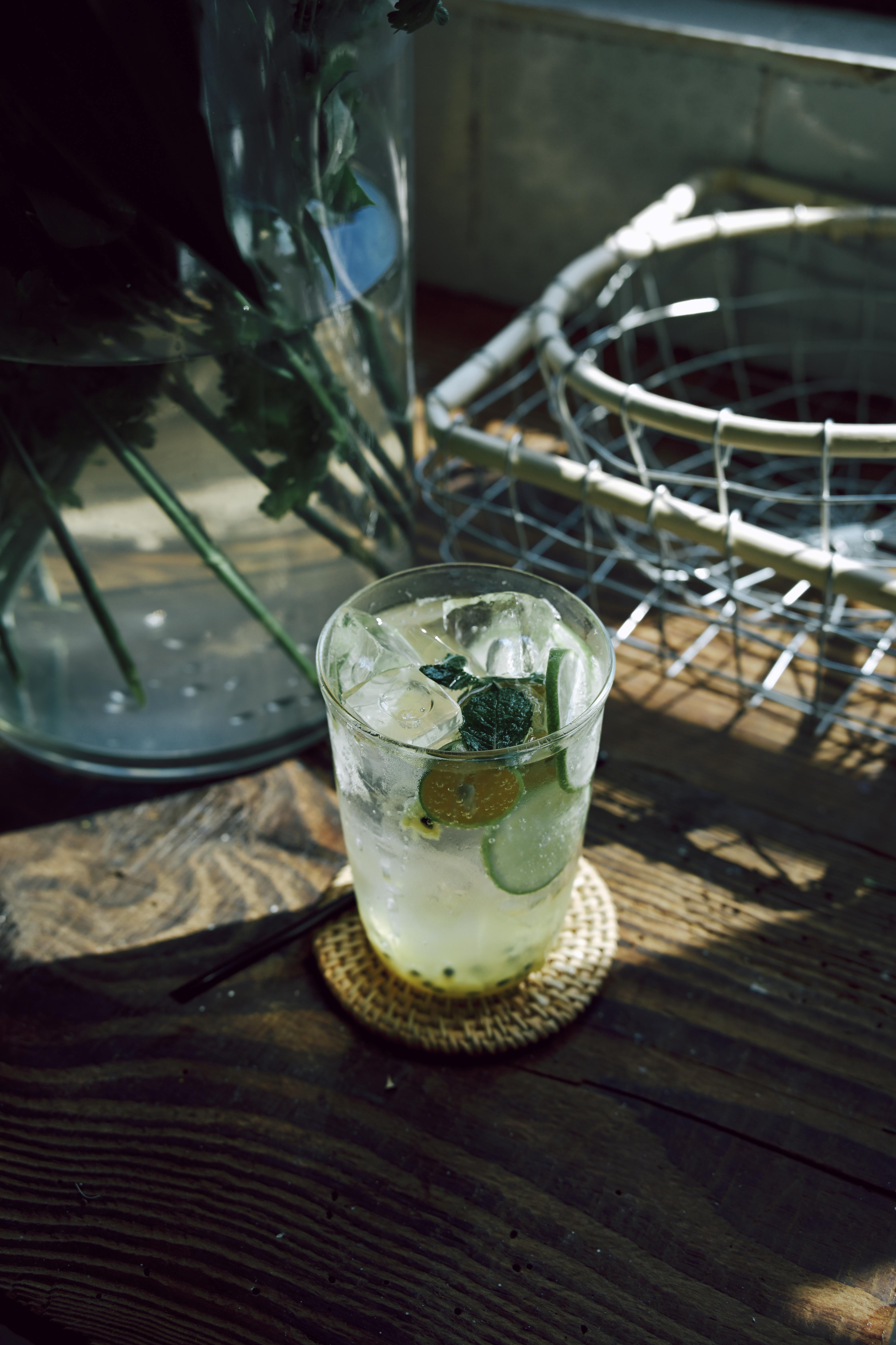 бесплатная На простом деревенском столике, залитом ярким естественным светом, стоит цитрусовый коктейль, украшенный листьями мяты. Стоковое фото