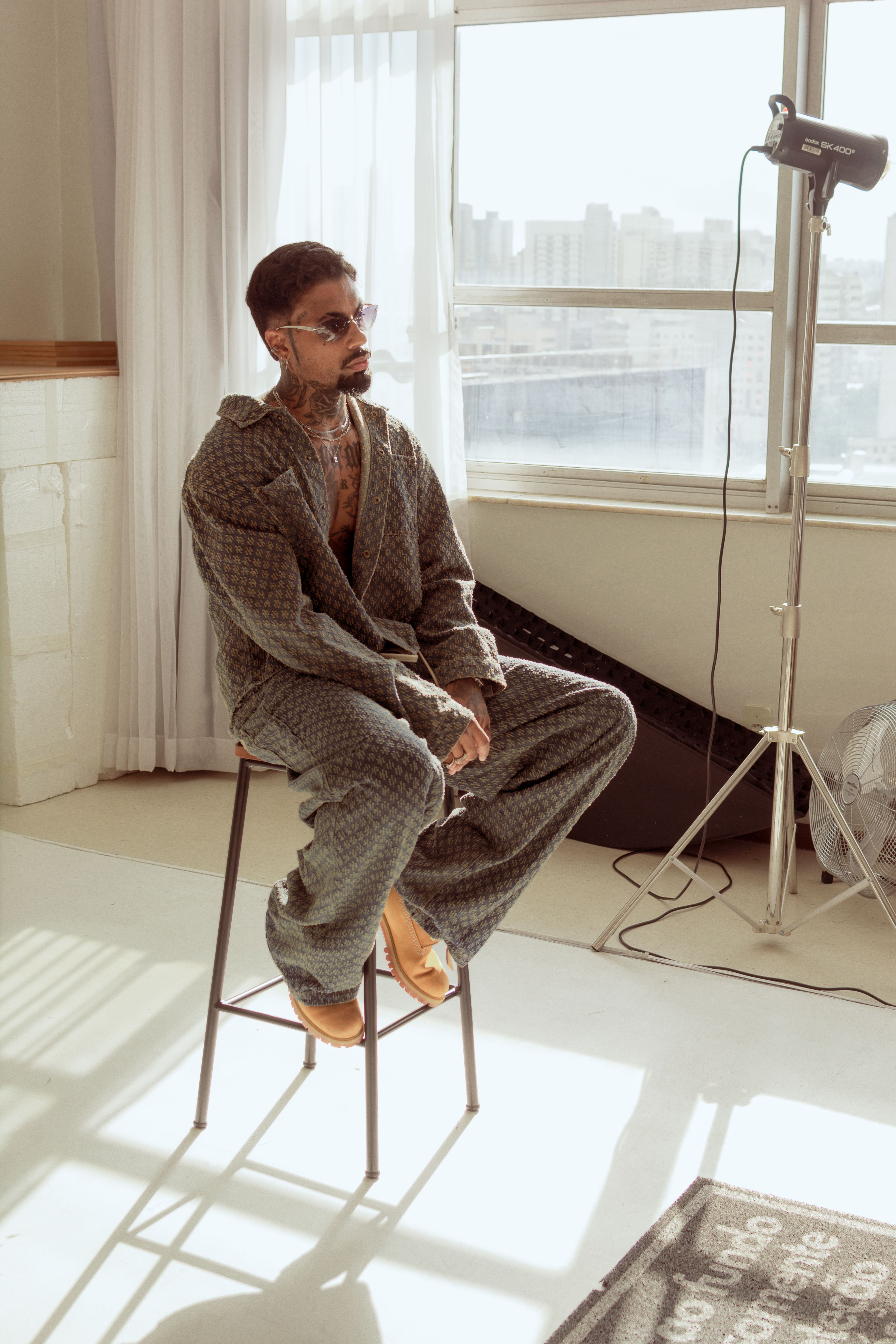 Stylish man in a modern urban studio with city view, showcasing fashion and design.