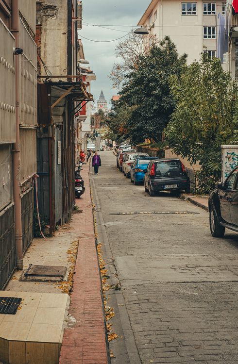 Narrow Urban Street with Cars and Distant Tower · Free Stock Photo