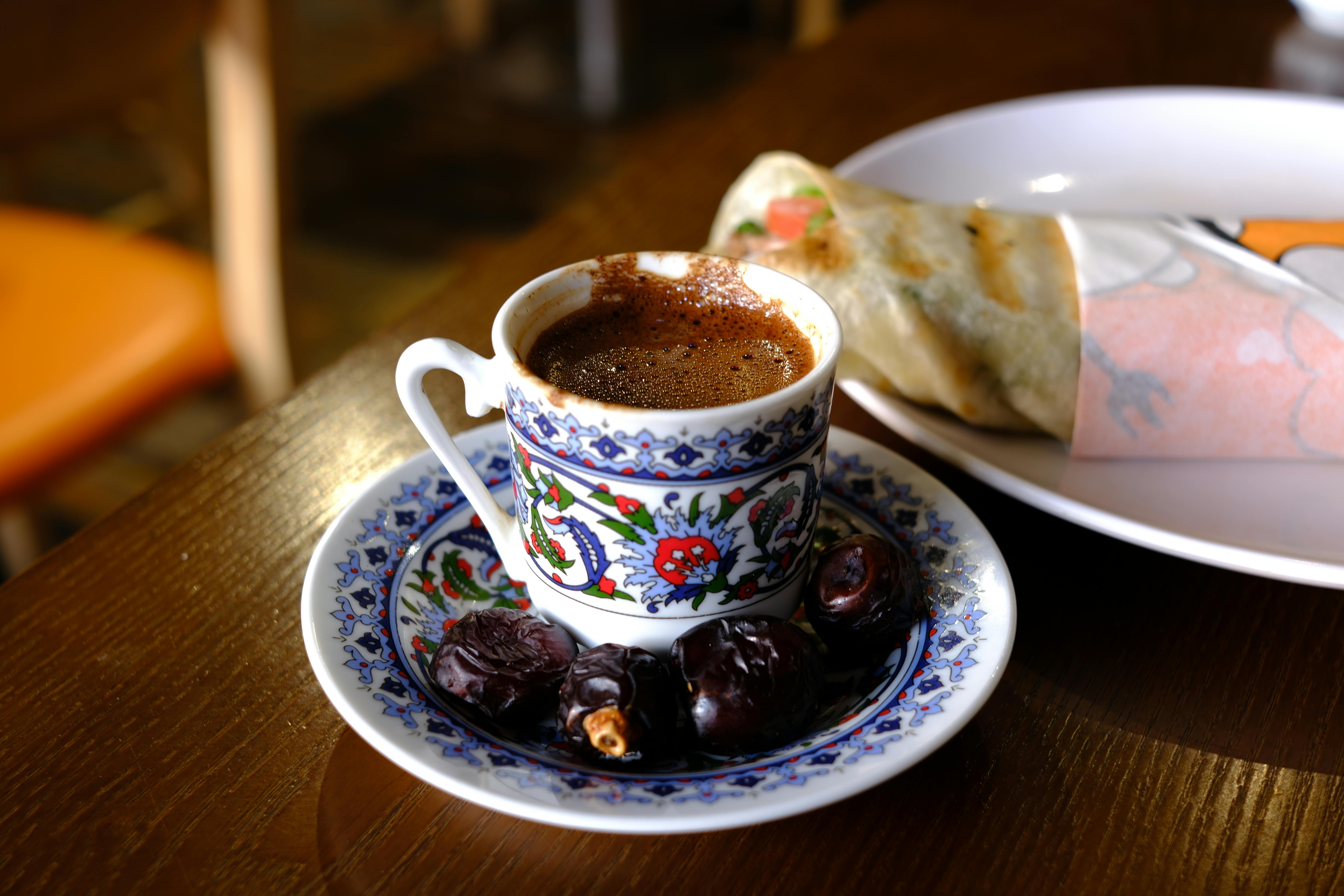 бесплатная Настоящий турецкий кофе, подаваемый с финиками в традиционной чашке с блюдцем и узором. Стоковое фото