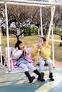 Children Enjoying Snacks on Park Swing in Winter