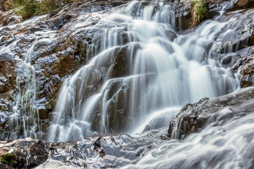Free Tranquil waterfall with smooth flowing water over rocks in a serene natural setting. Stock Photo