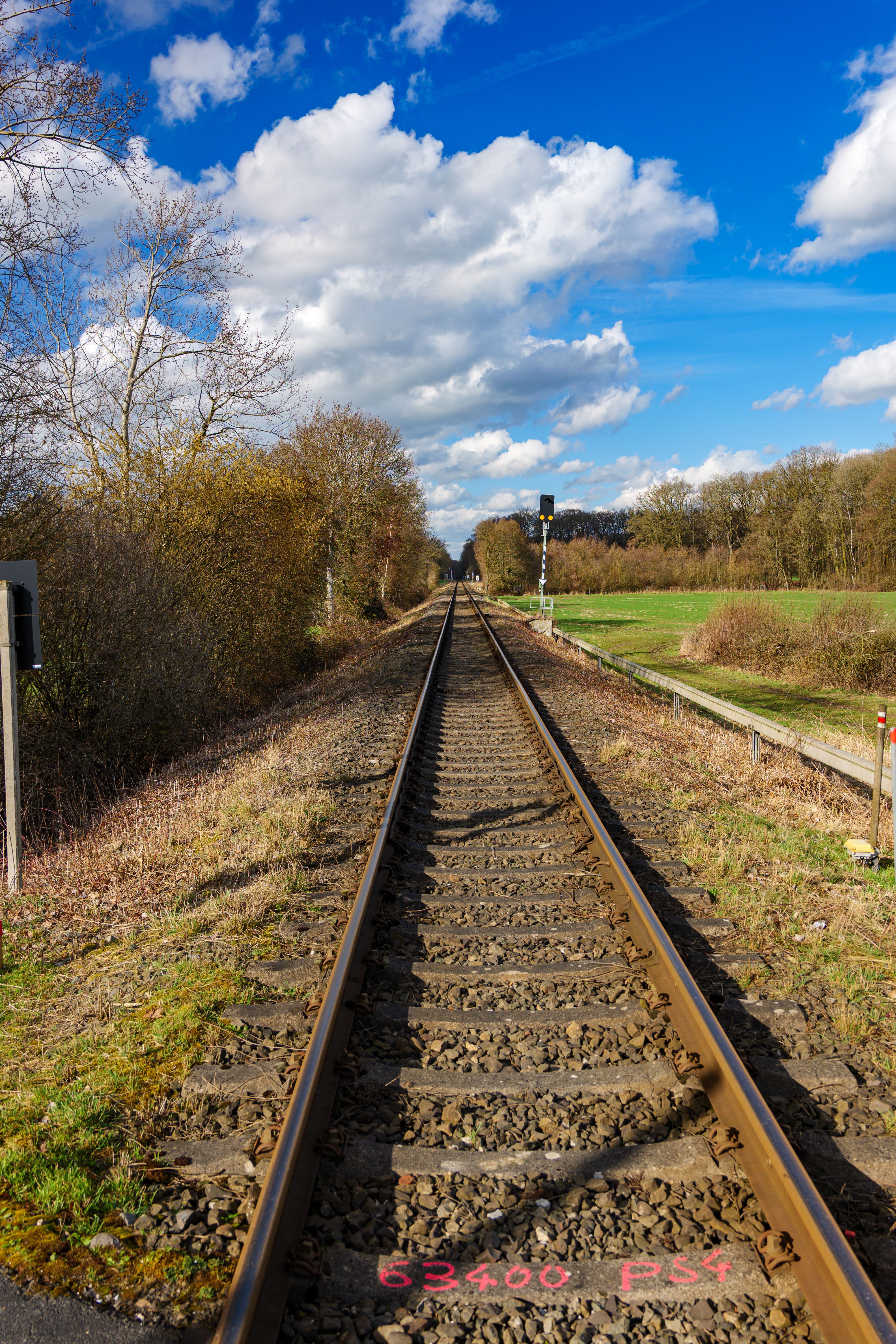 Railroad tracks leading into the distance under a bright blue sky with clouds in Coesfeld, Germany.