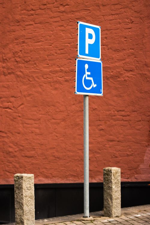 Free A blue disabled parking sign in front of a red brick wall in Jönköping, Sweden. Stock Photo