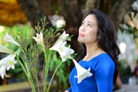 Woman in Blue Dress Holding White Lilies Outdoors