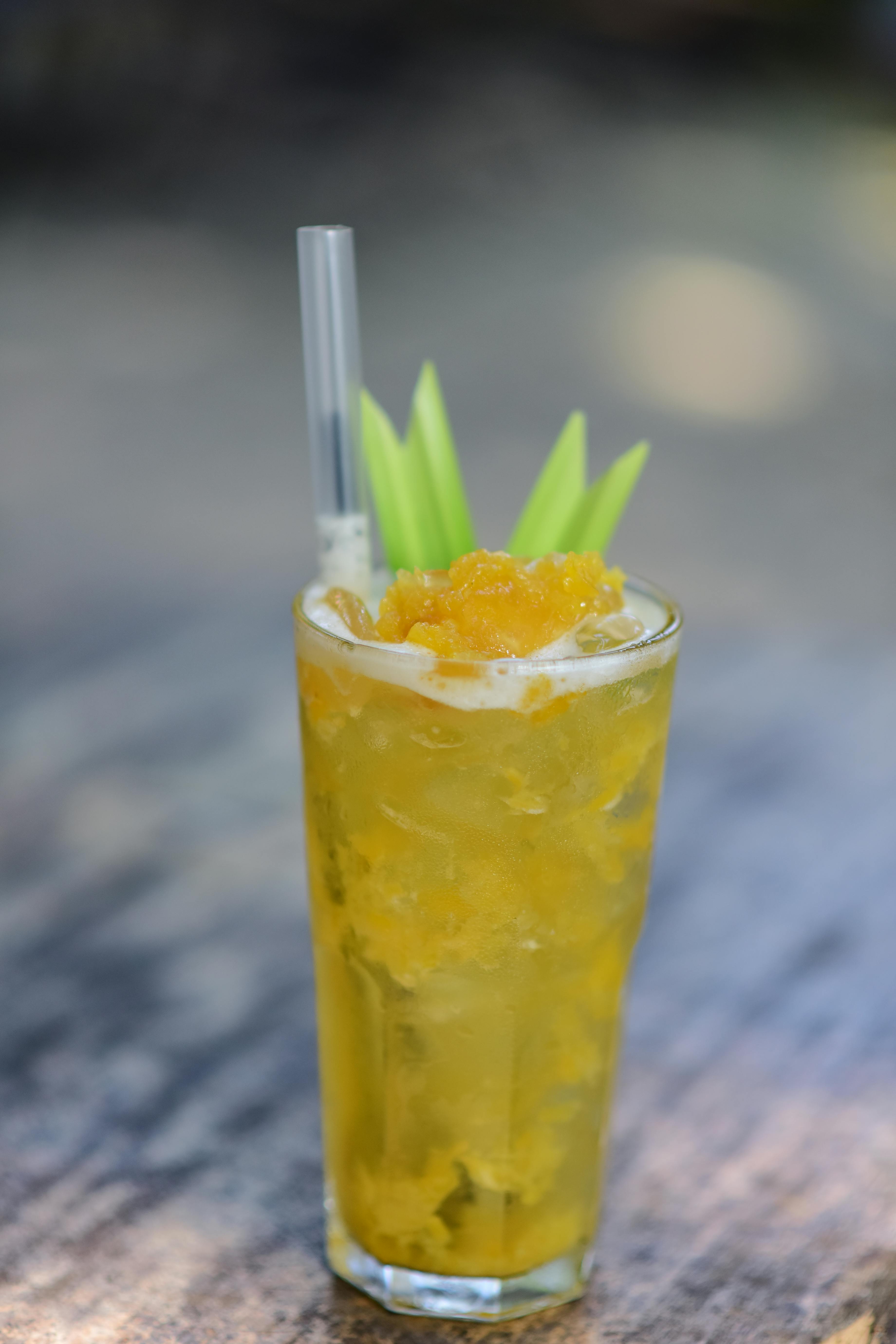 бесплатная Высокий стакан с охлажденным манговым напитком, трубочкой и украшением, на открытом воздухе. Стоковое фото