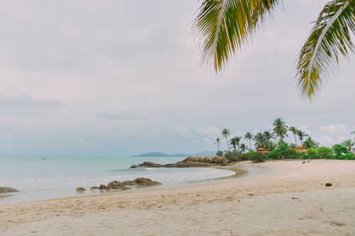 Free Tranquil beach scene with palm trees and clear blue water at Bangka Belitung Islands, Indonesia. Stock Photo