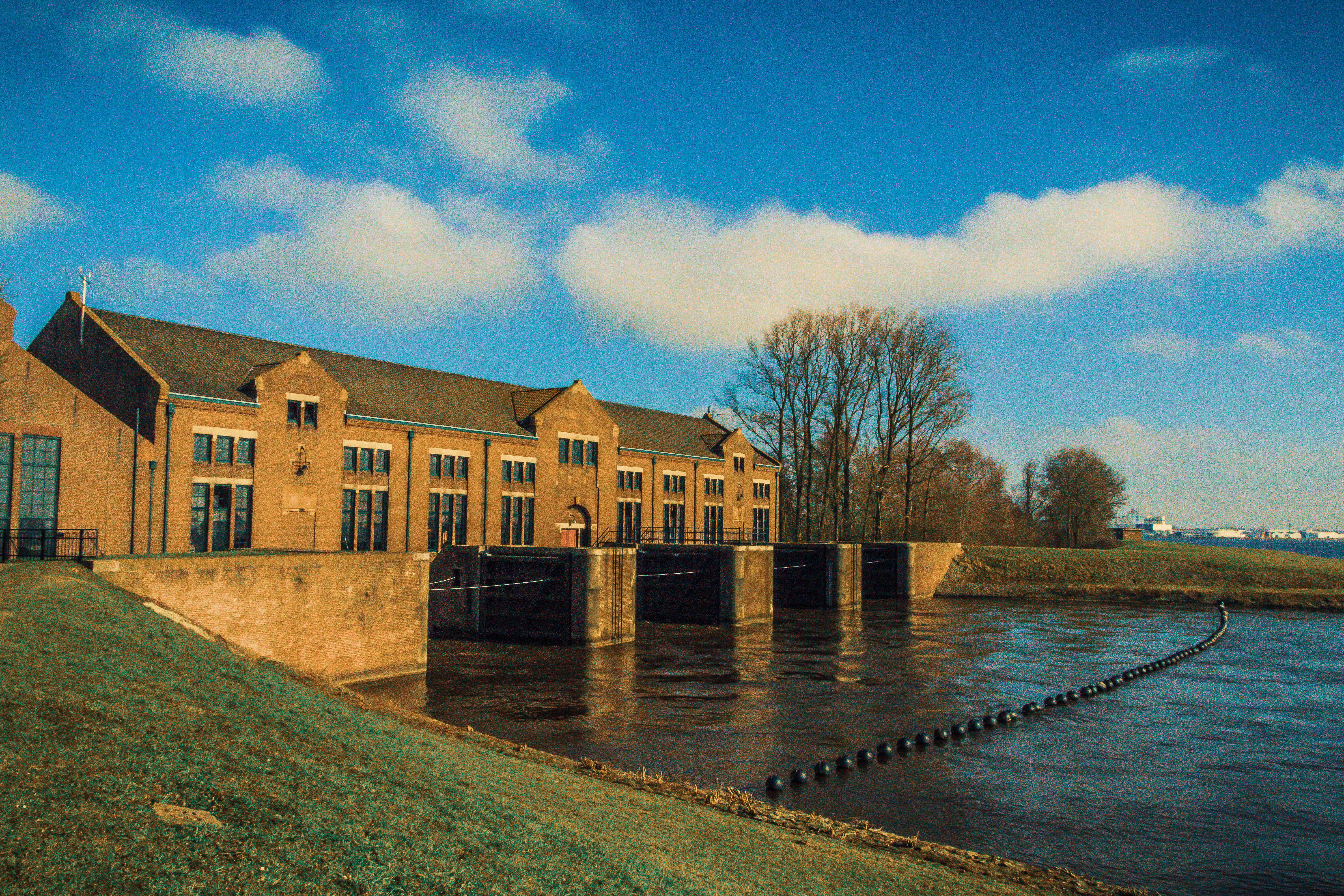 Historic Pumping Station by River on Sunny Day · Free Stock Photo