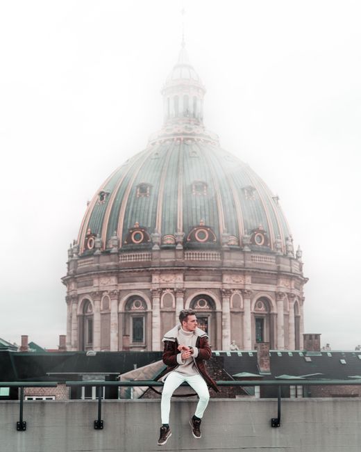 Fashionable man sits near famous dome, blending modern style with historic architecture.