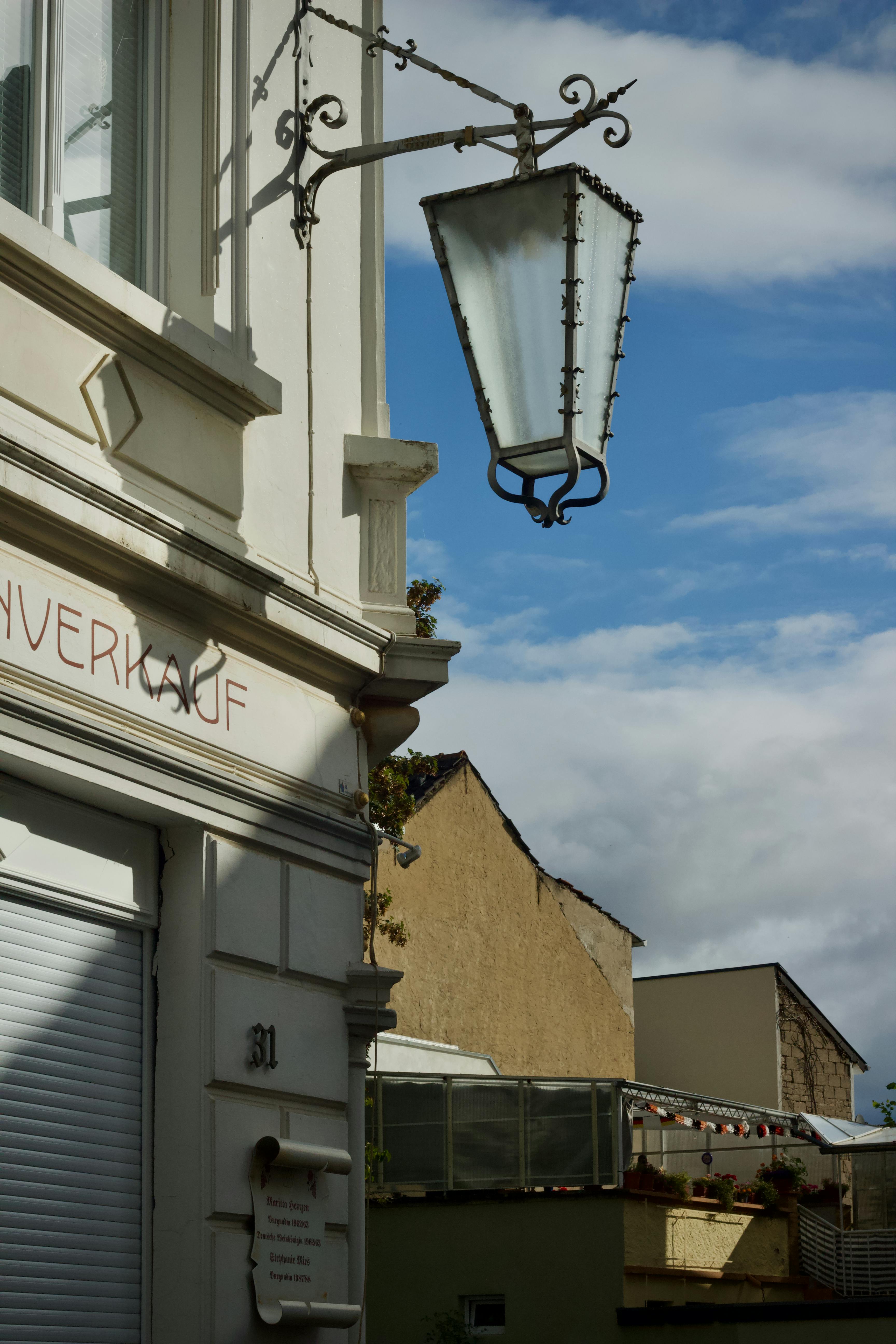 A quaint European street featuring a vintage lamp, classic architecture, and blue skies.