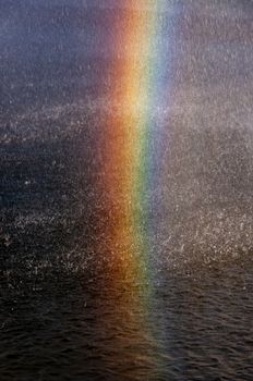 A stunning rainbow over a waterfall splashes with vibrant sunlight and water droplets.