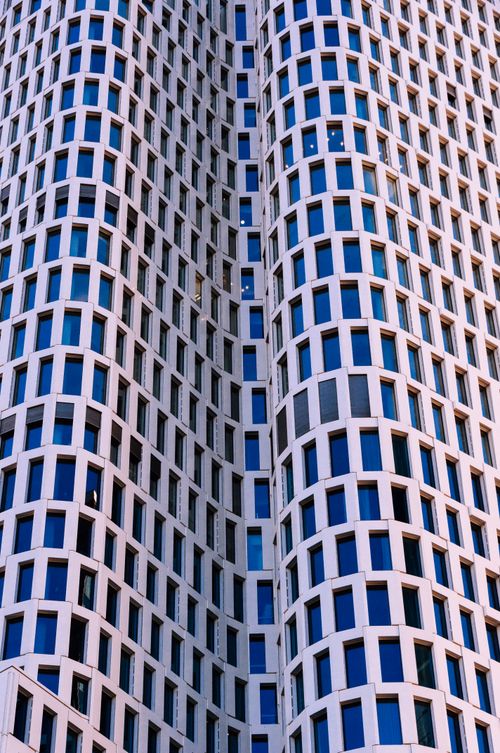 Free Captivating upward view of a modern high-rise building facade with symmetric window patterns. Stock Photo
