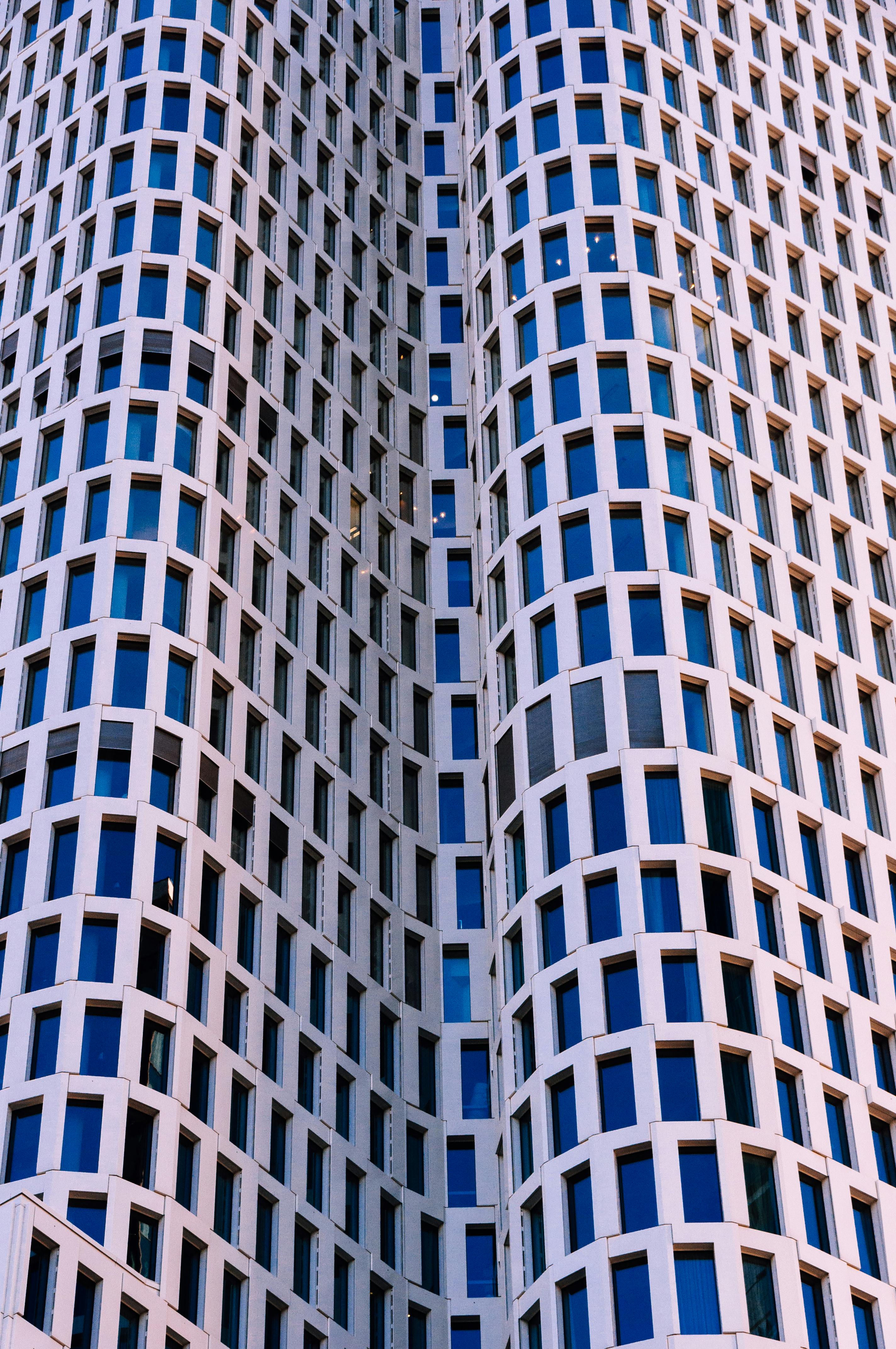 gratis Een fascinerend uitzicht omhoog op de gevel van een modern hoog gebouw met symmetrische raamindeling. Stockfoto