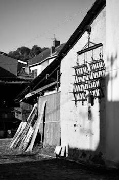 Black and white photo highlighting shadow art on rural farmhouse exterior.