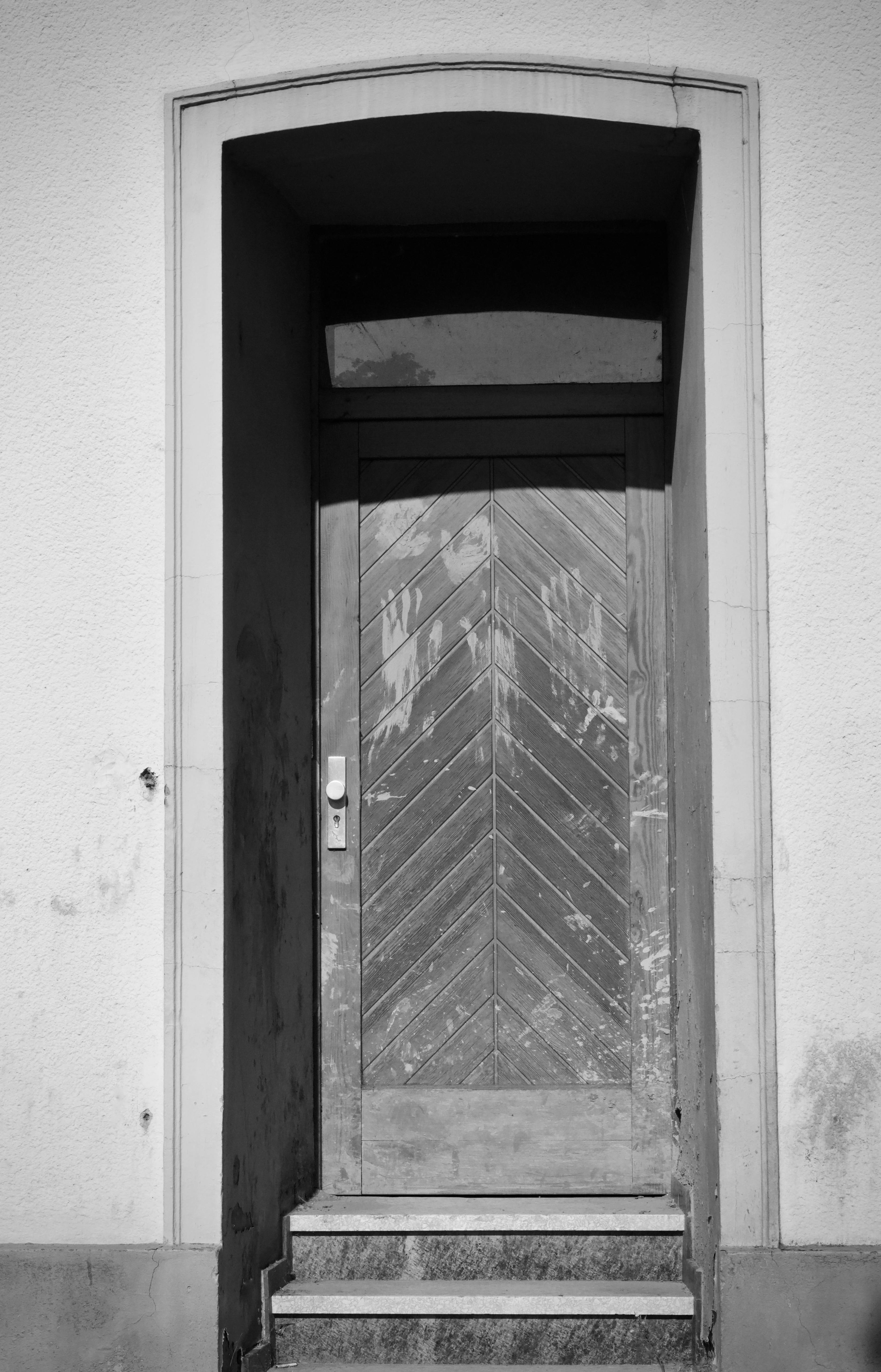 Zadarmo Čiernobiela fotografia starých drevených dverí orámovaných betónovou architektúrou. Fotka z fotobanky