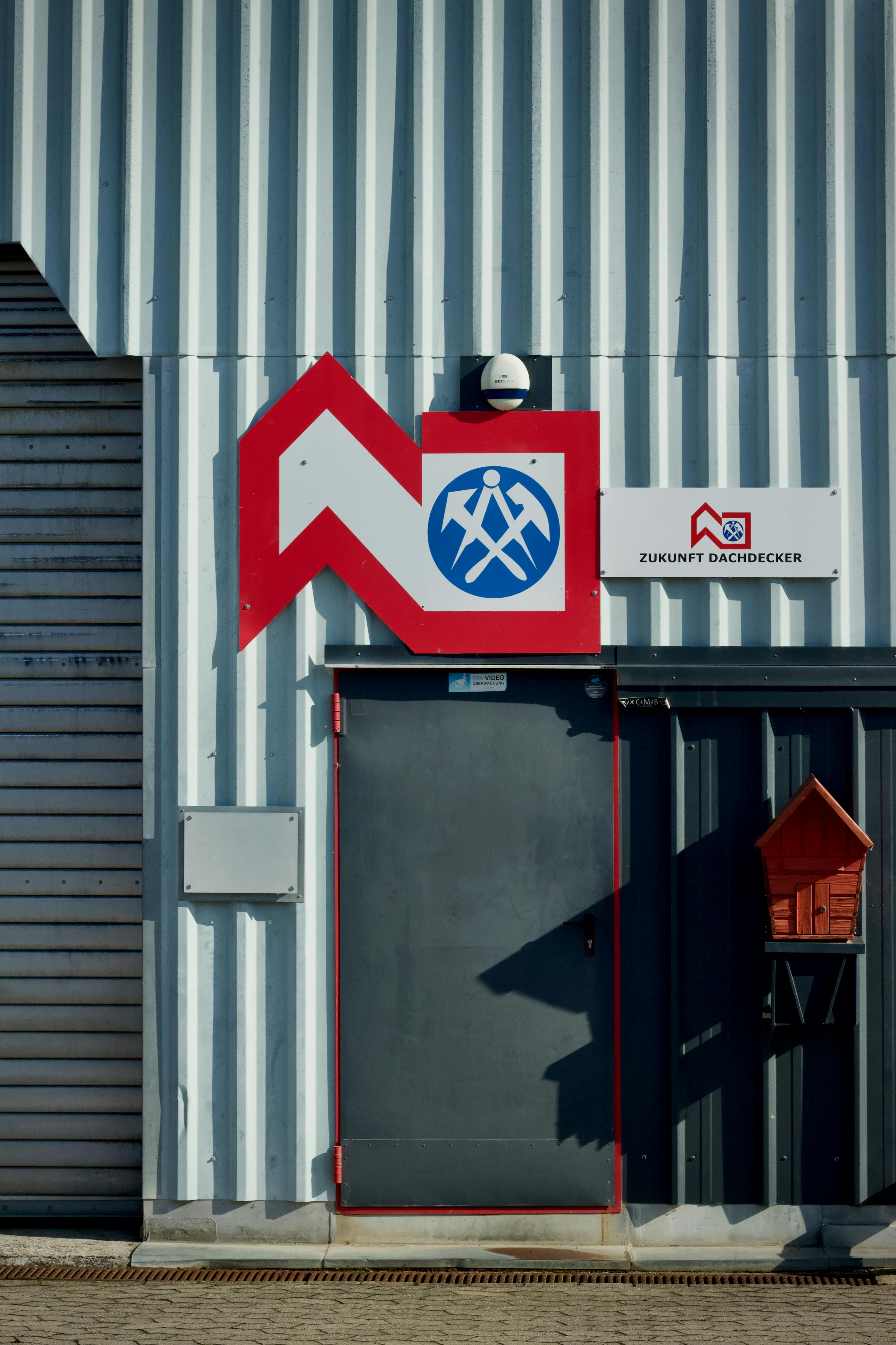 Exterior of industrial building with Zukunft Dachdecker signage and corrugated metal paneling.
