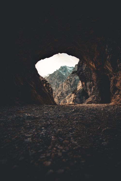 Free Scenery view of cave surrounded by rough mounts and uneven dry terrain with natural arched entrance in daytime Stock Photo