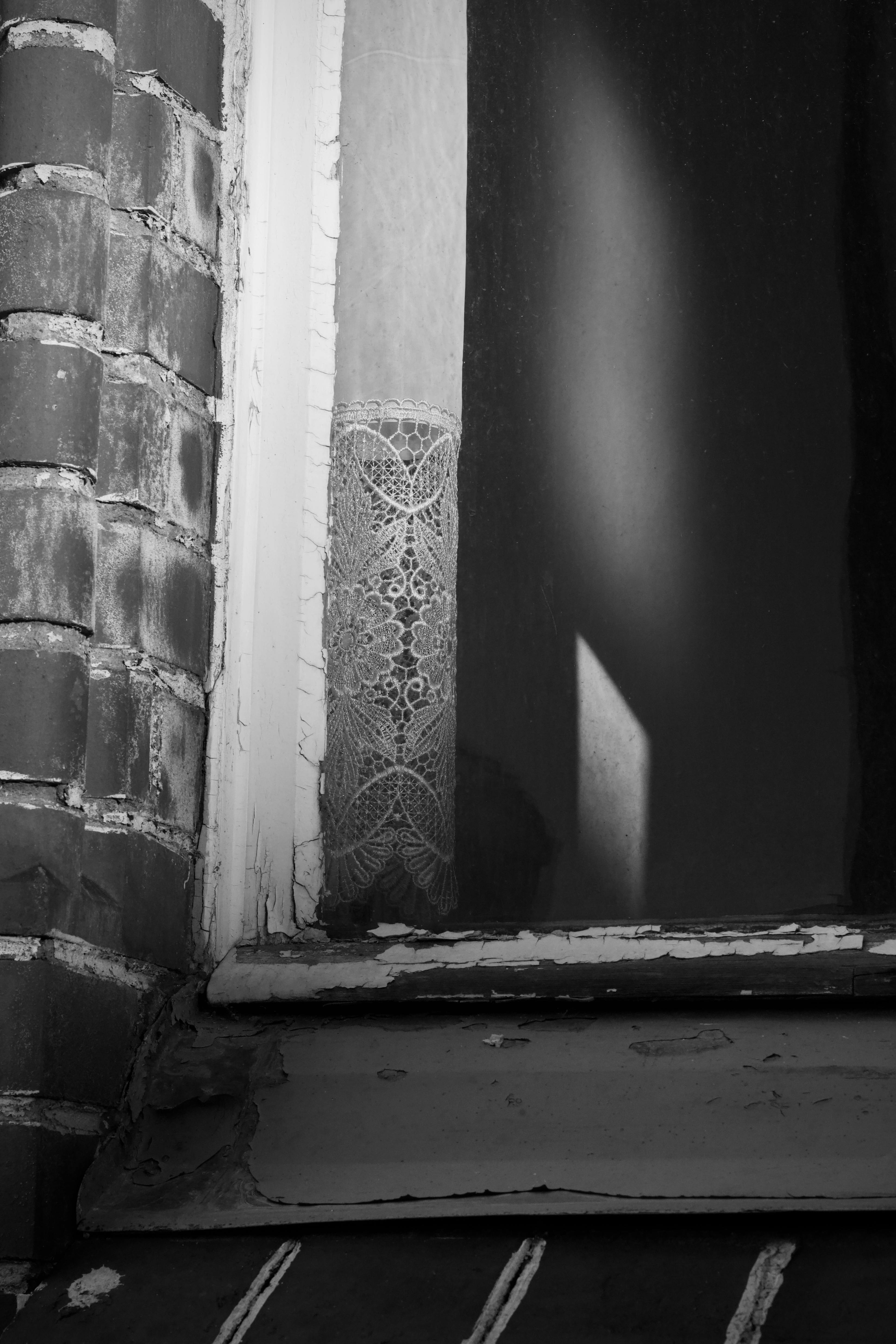 Bezpłatne Stara ceglana ściana z rustykalnym oknem i monochromatyczną koronkową zasłoną. Zdjęcie z galerii