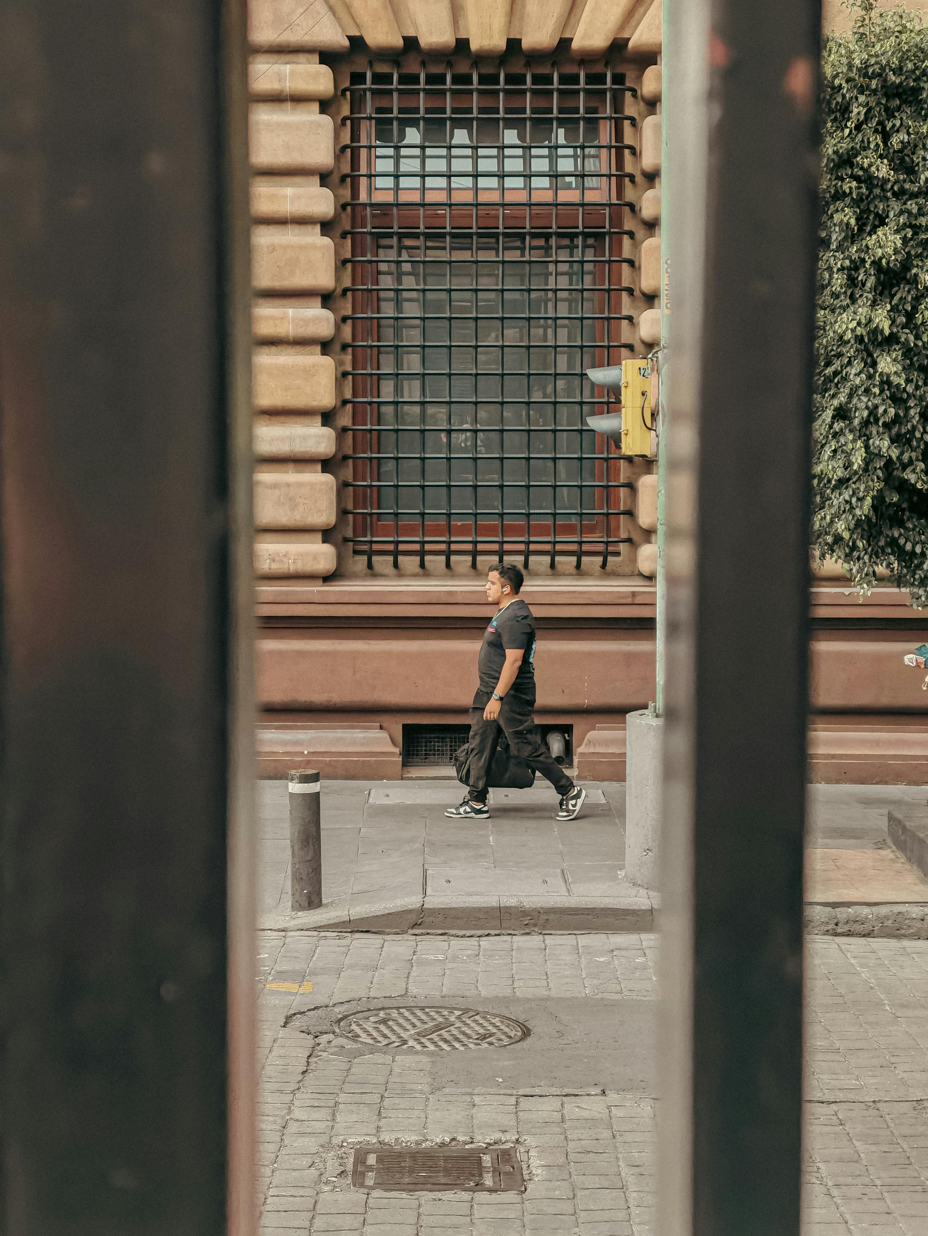 Kostenlos Ein Mann spaziert durch Mexiko-Stadt, eingerahmt von Architektur, die eine faszinierende urbane Straßenszene erzeugt. Stock-Foto