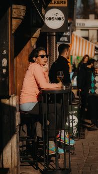 A woman in sunglasses relaxes outside a cafe, enjoying a sunny day.