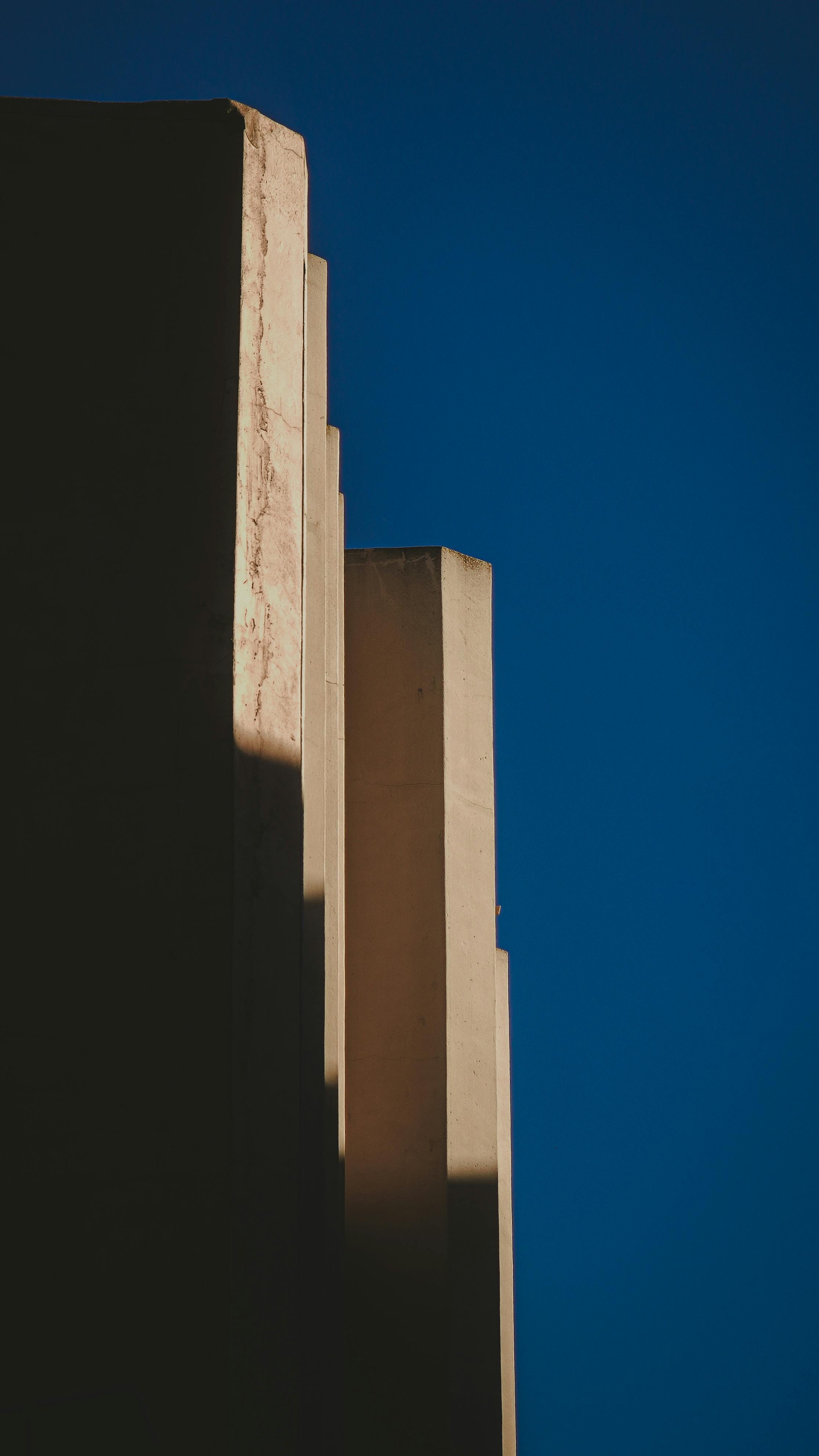 Free Close-up of a modern building's abstract form with sharp lines against a clear blue sky. Stock Photo