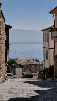 Cobblestone street in a quaint coastal village with sea view, perfect for travel inspiration.