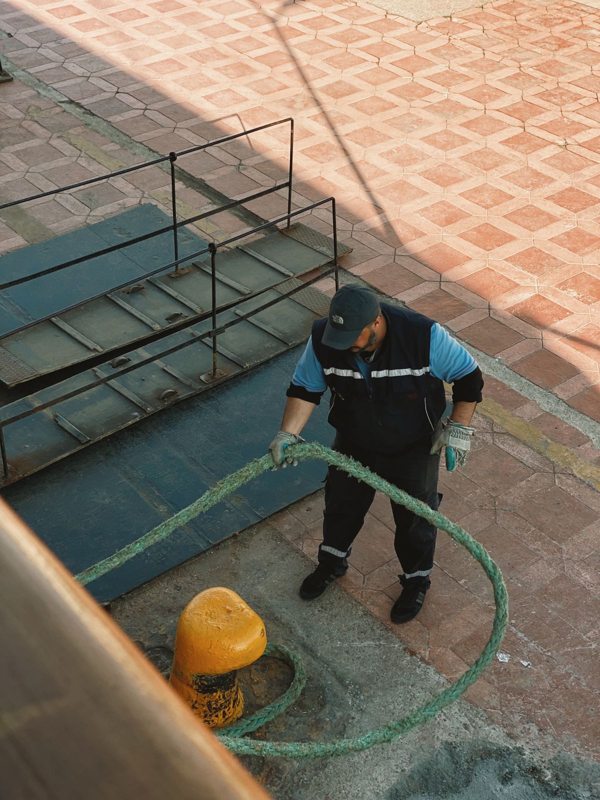 Dock worker coiling a mooring rope on the quay at the harbor