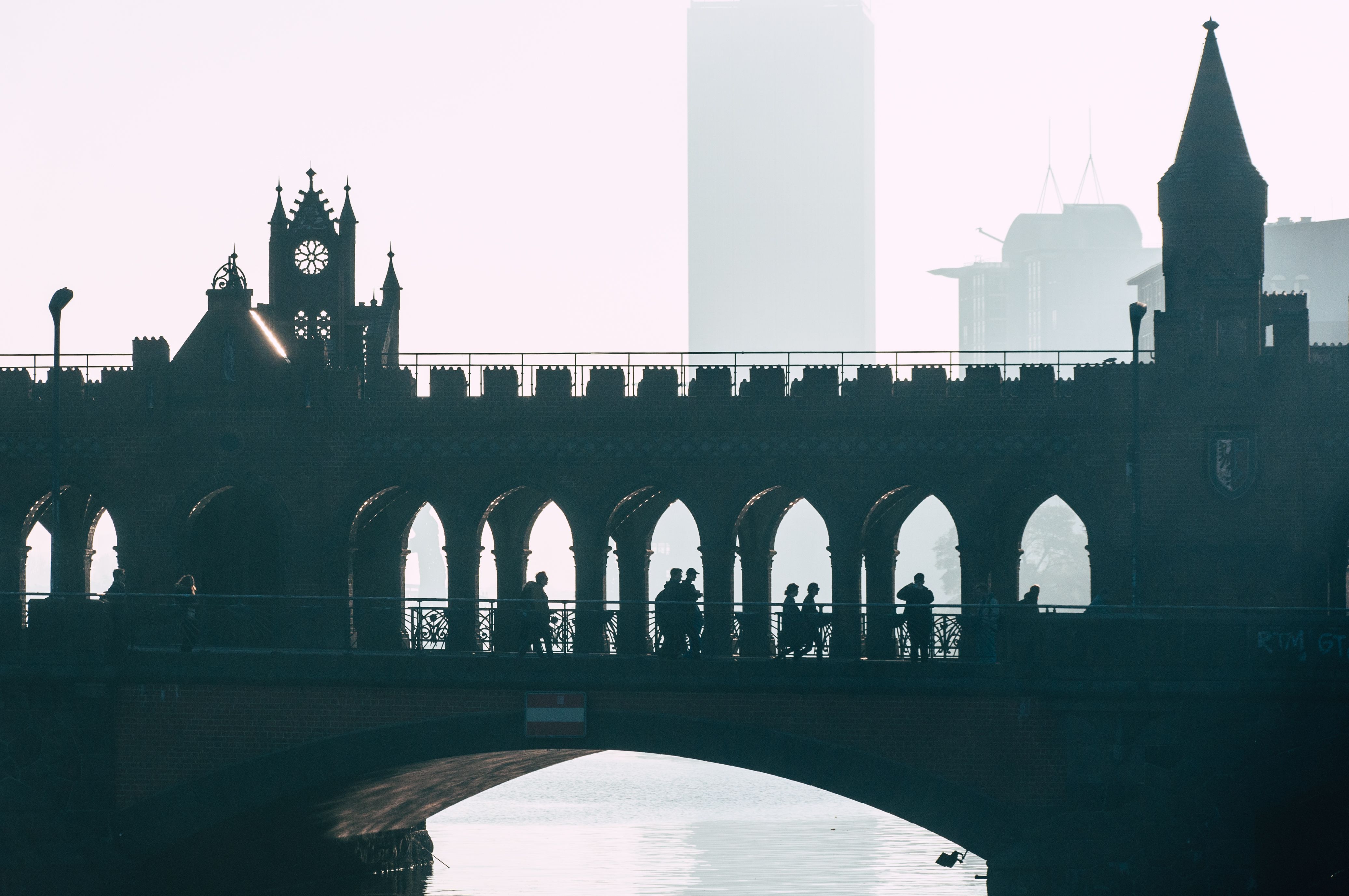 A stunning silhouette of people walking on the iconic Oberbaum Bridge in Berlin during dusk.