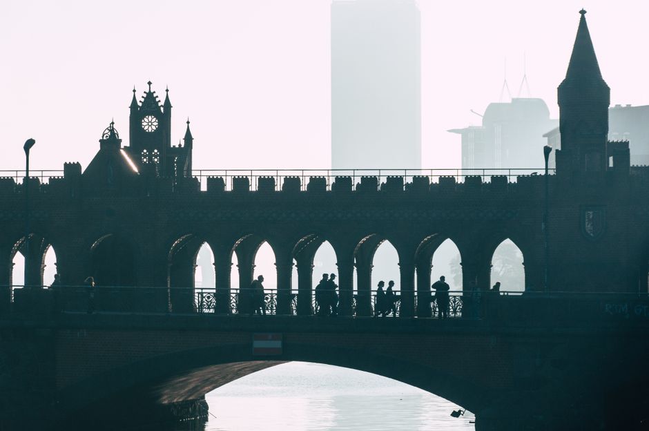 A stunning silhouette of people walking on the iconic Oberbaum Bridge in Berlin during dusk.